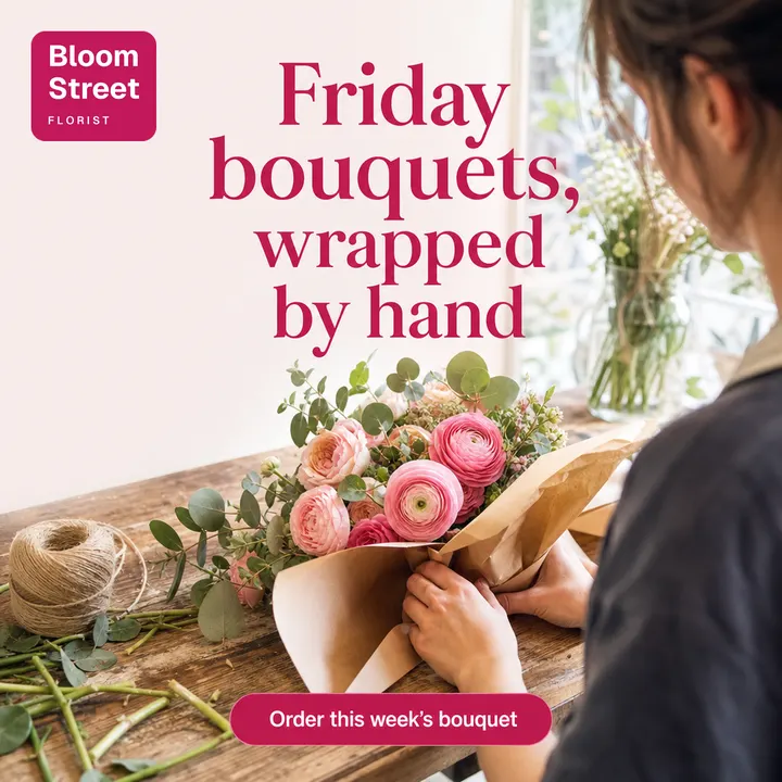 AI-generated lifestyle photo for Bloom Street Florist: a florist's hands wrapping pink ranunculus and roses in brown paper on a wooden bench, with the headline “Friday bouquets, wrapped by hand”, an “Order this week's bouquet” button and the Bloom Street logo.